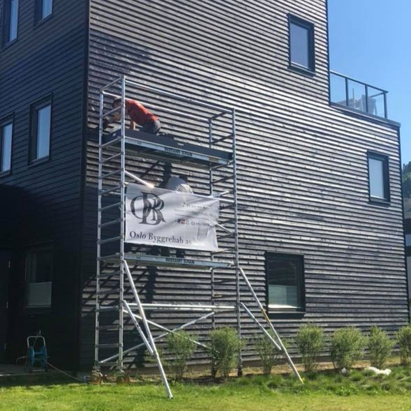 en Oslo Byggrehab AS ansatt som jobber med utsiden på hjørnet av et rekkehus på et stilas