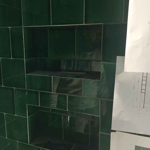 Et bad midt i prosessen med å bli flislagt med en innebygd hylle i dusjen