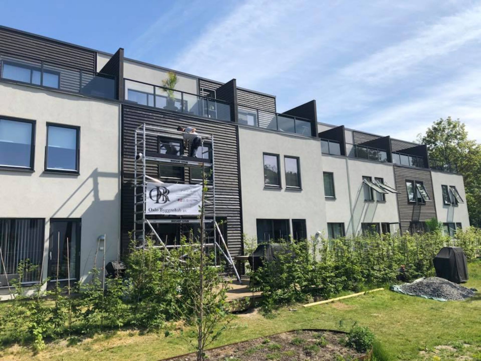 en Oslo Byggrehab AS ansatt som jobber med utsiden av et rekkehus på et stilas