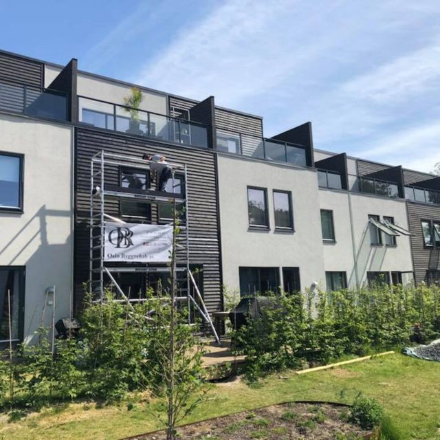 en Oslo Byggrehab AS ansatt som jobber med utsiden av et rekkehus på et stilas
