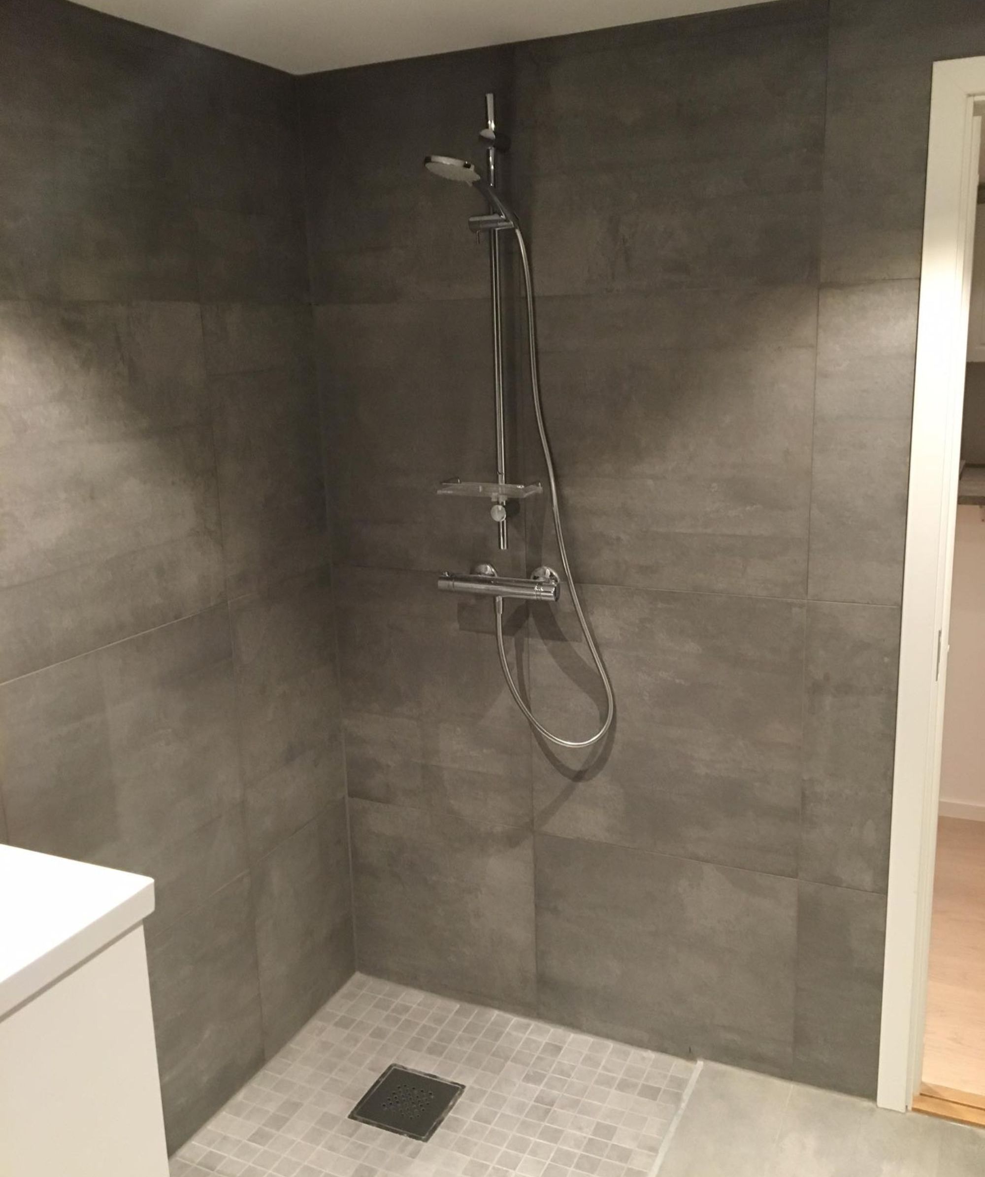 Moderne bad med en dusj og grå røffe vegger