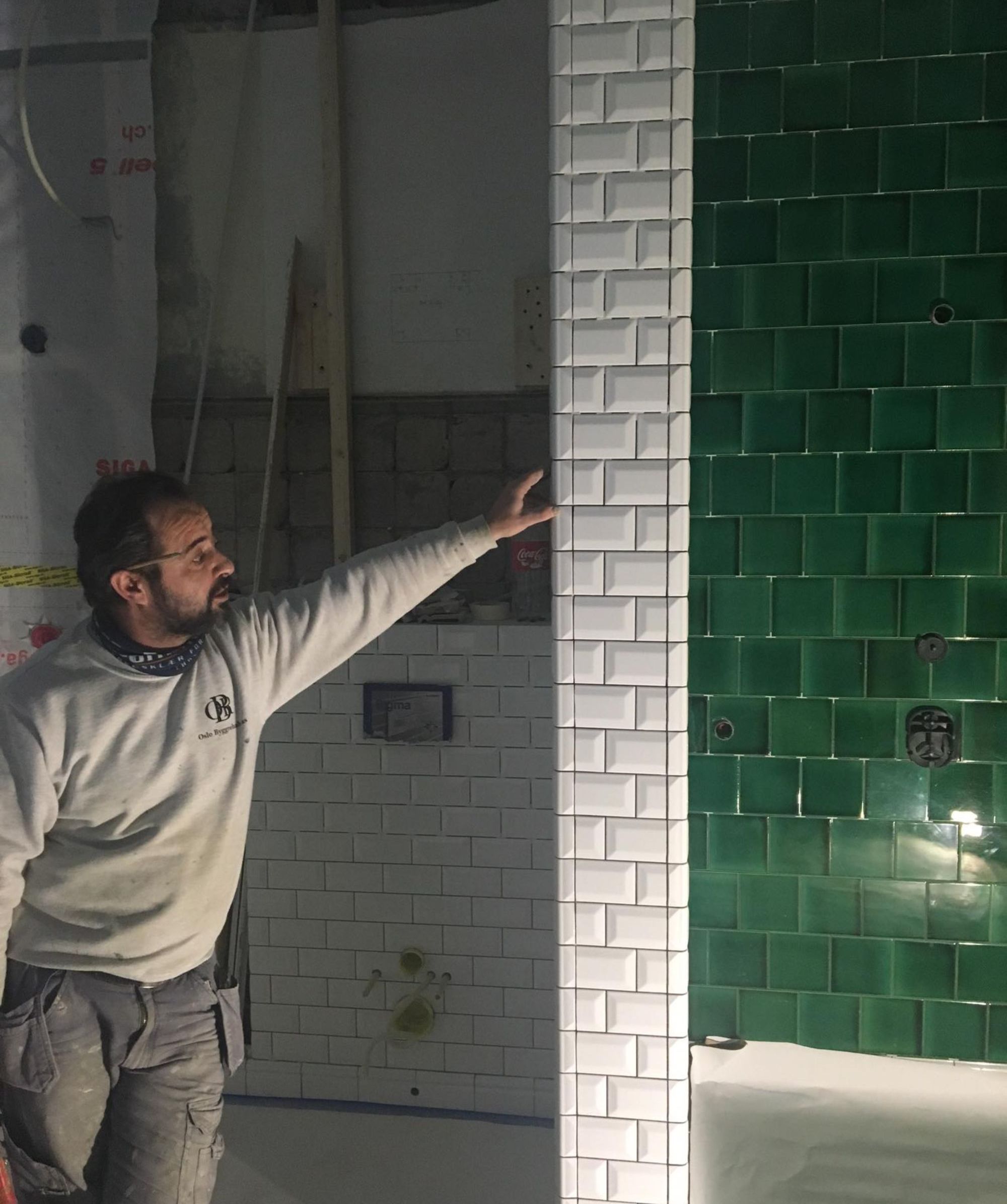 En Oslo Byggrehab AS ansatt som står og inspiserer flisarbeidet som er gjort på et bad